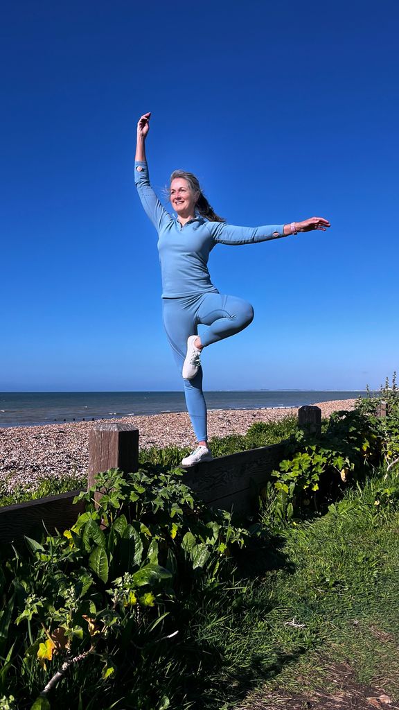 Woman balancing on one left against a blue backdrop 