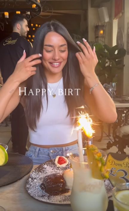 A woman in front of a birthday cake