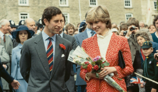 Prince Charles standing next to Princess Diana holding a bunch of flowers