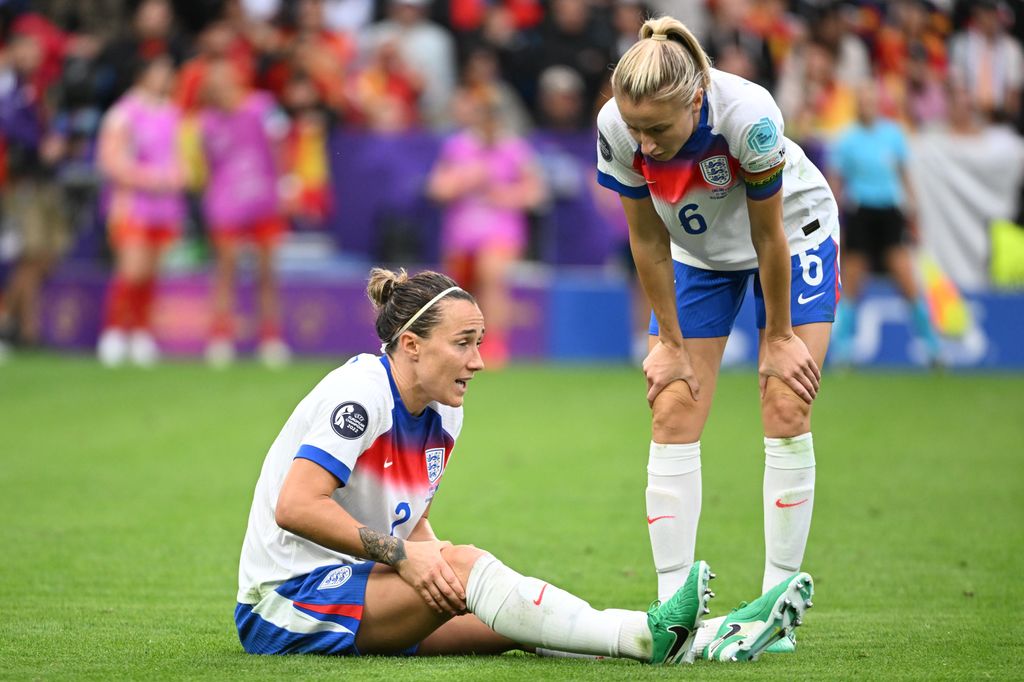 Lucy Bronze of England (l) sitting injured on the field and talking with Leah Williamson of England (r) during the UEFA Women's EURO 2025 Final match between England and Spain at St. Jakob-Park on July 27, 2025 in Basel, Switzerland