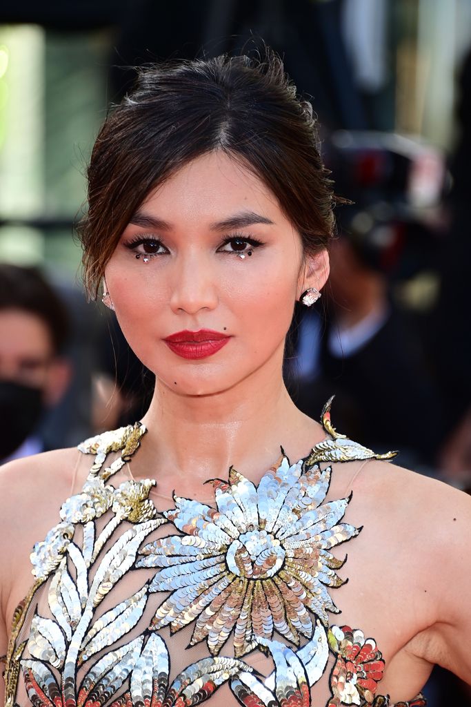 Gemma Chan with a red lip and gem studs under her eyes 