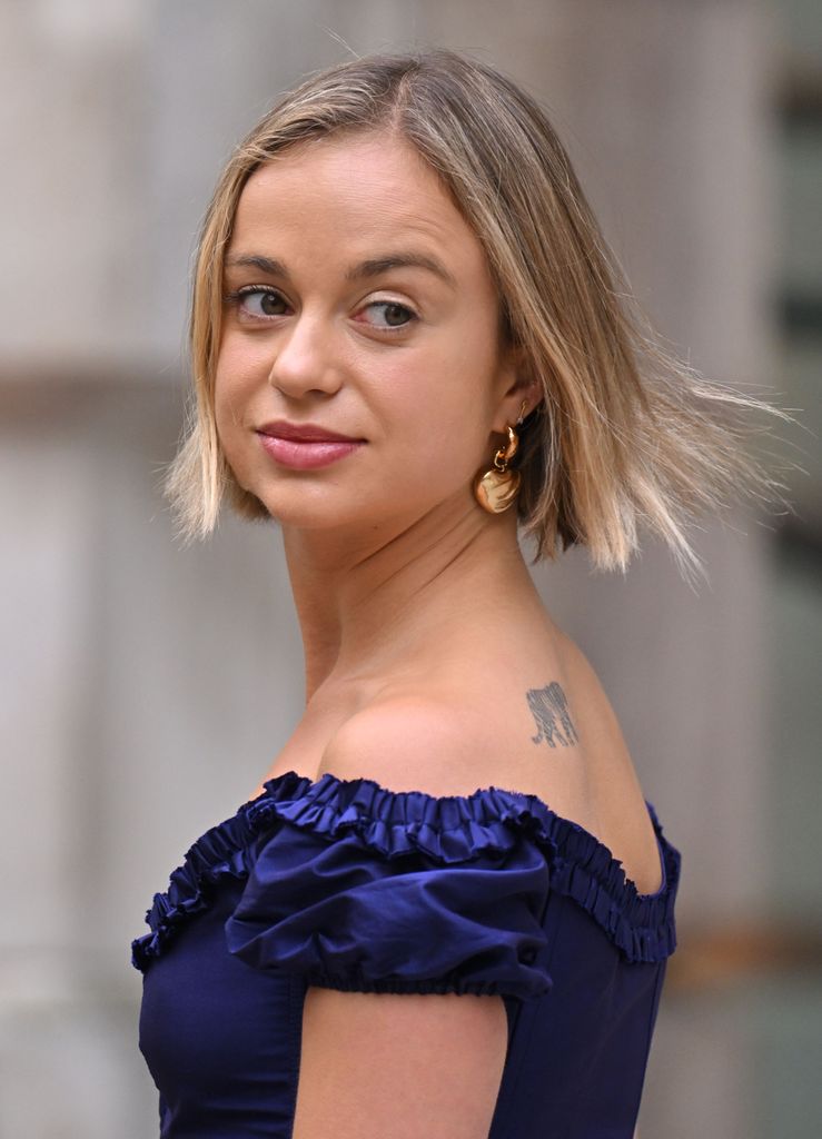 Lady Amelia Windsor looking over her shoulder in a blue off the shoulder dress