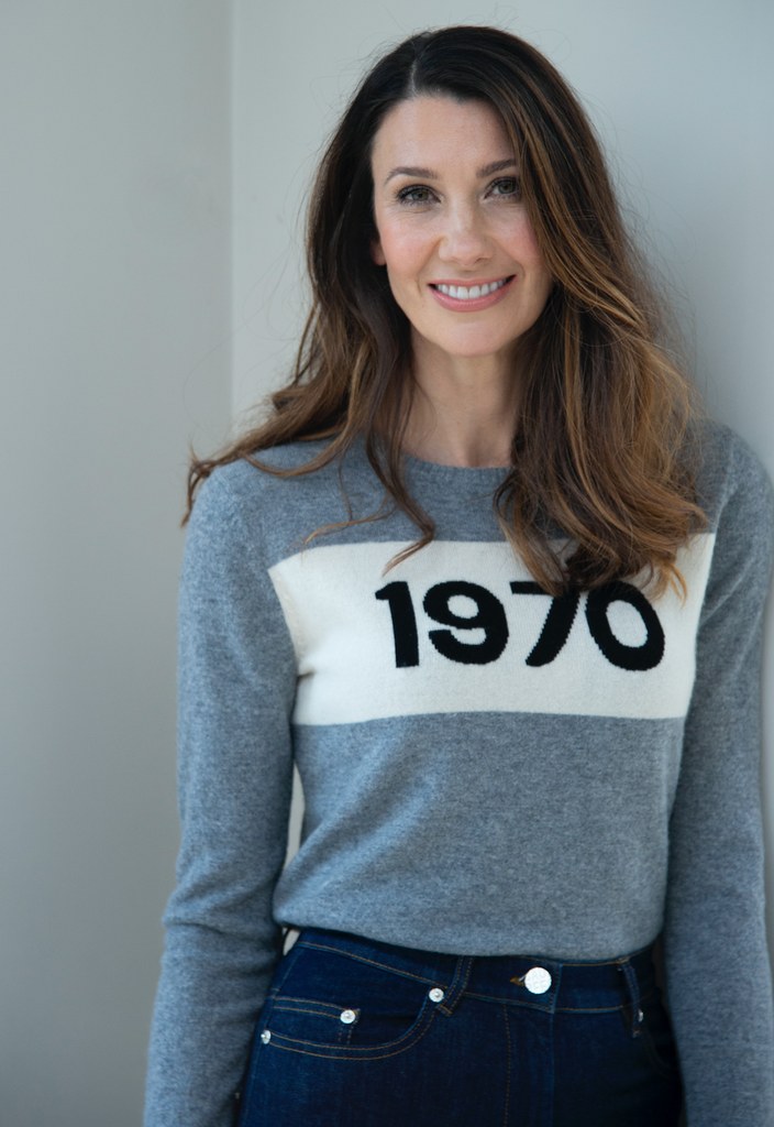 Woman smiling in grey jumper and jeans