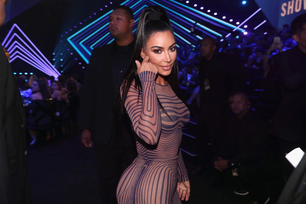Kim Kardashian smiling at the camera while turning towards it and flicking her hair