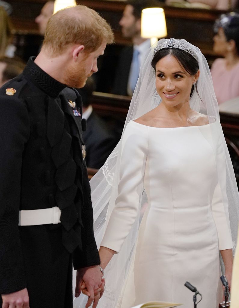 Meghan Markle in her wedding dress and tiara smiling at Harry on their wedding day