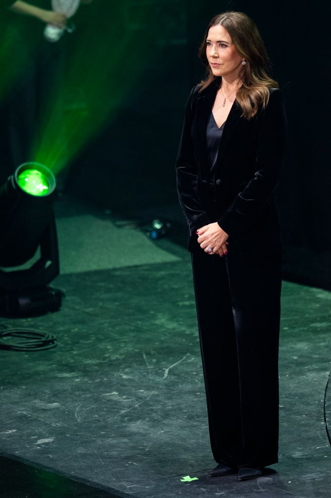 Queen Mary on stage in black velvet suit
