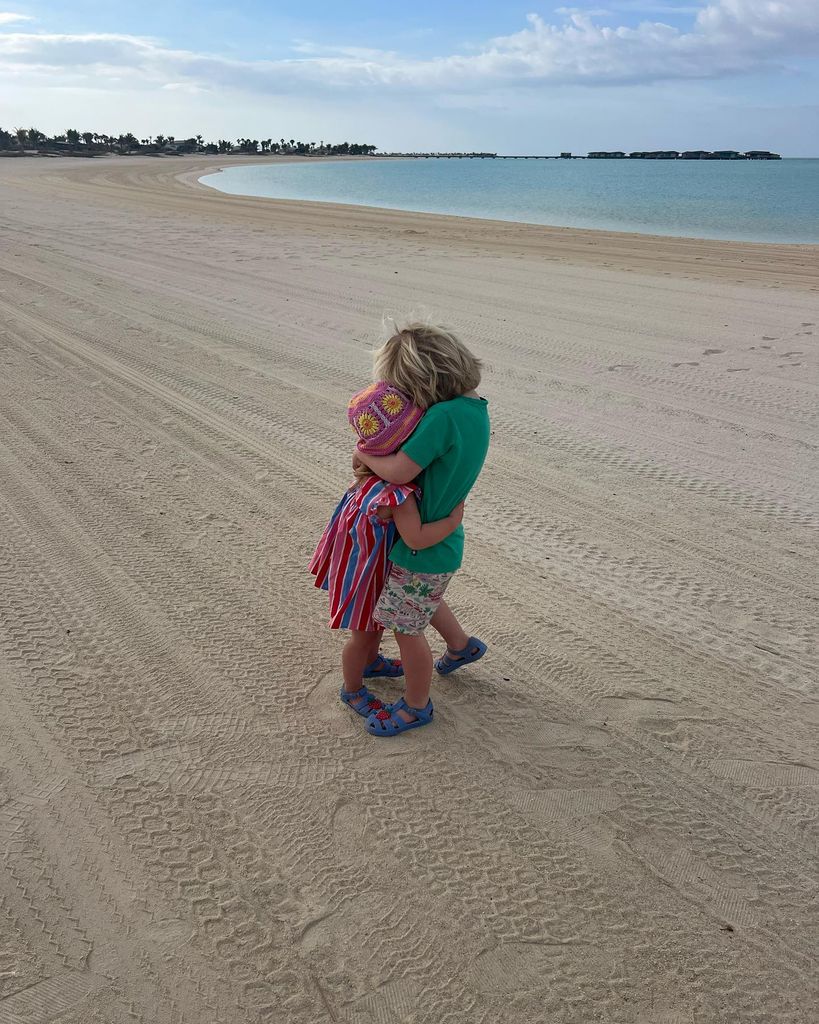 brother and sister hugging on the beach