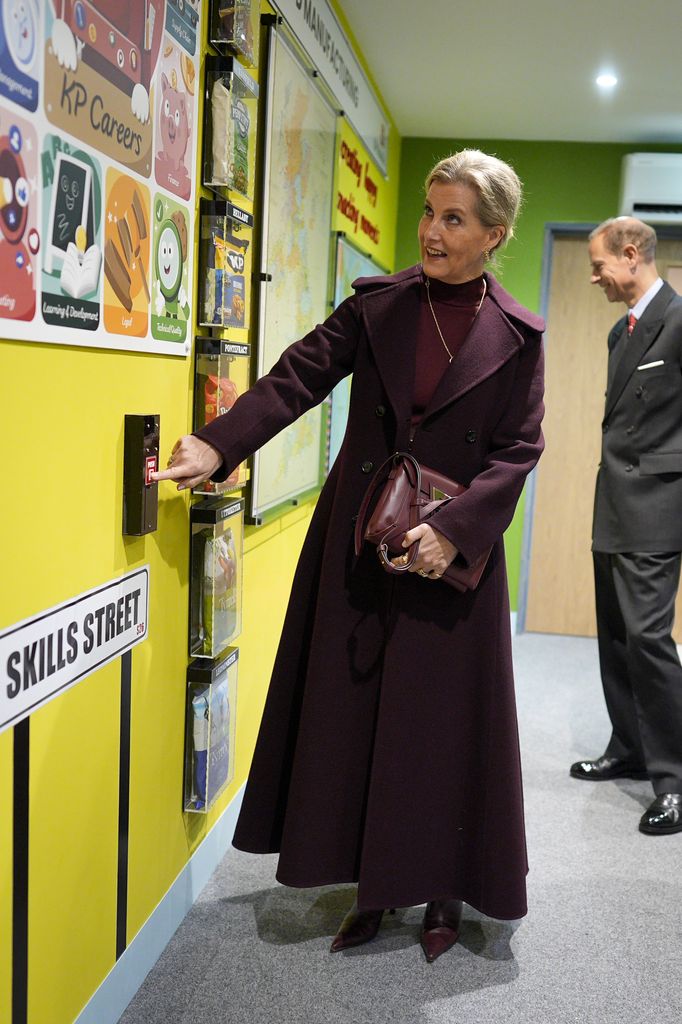 La duchesse d'Édimbourg montrant le mur en robe et bottes bordeaux