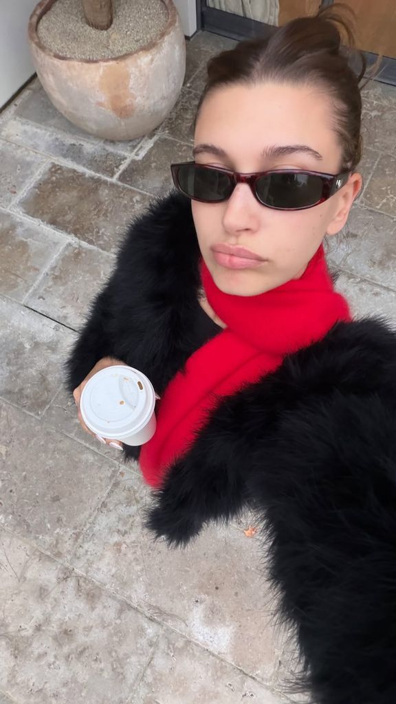 Hailey Bieber shares a selfie of herself wearing a red scarf and sunglasses