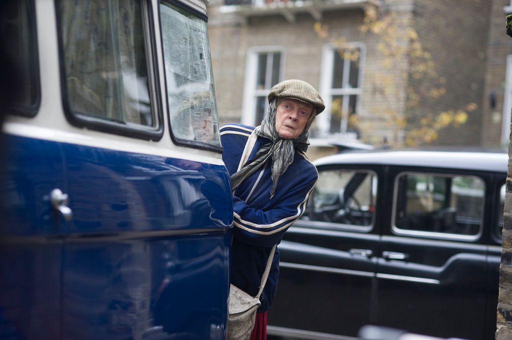 Dame Maggie Smith from behind a van in a still from The Lady in the Van