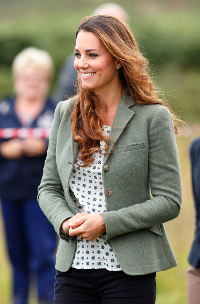 Kate smiling with curly hair in khaki blazer