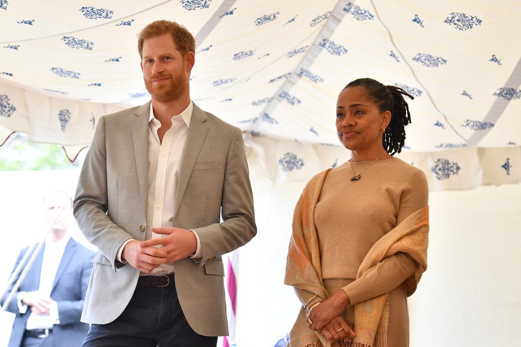 Prinz Harry im grauen Blazer und Doria Ragland im cremefarbenen Outfit