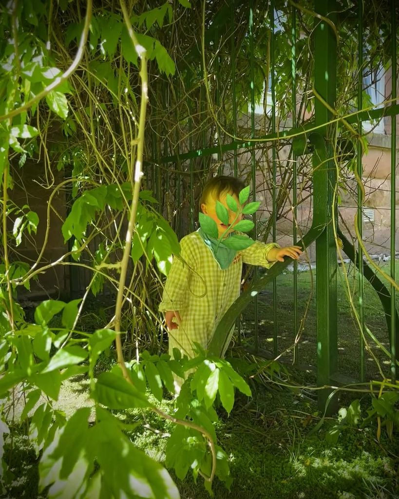 Natasha Raskin Sharp's baby standing among plants near the park in a photo shared on Instagram