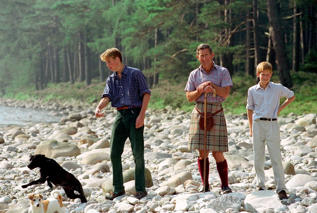 Then-Prince Charles In Kilt And Sporran And Shepherd's Crook Walking Stick With Prince William & Prince Harry At Polvier, By The River Dee, Balmoral Castle Estate in August 1997