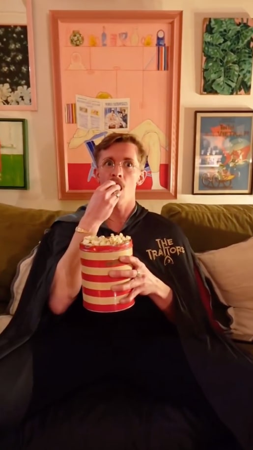 man sat on sofa eating popcorn