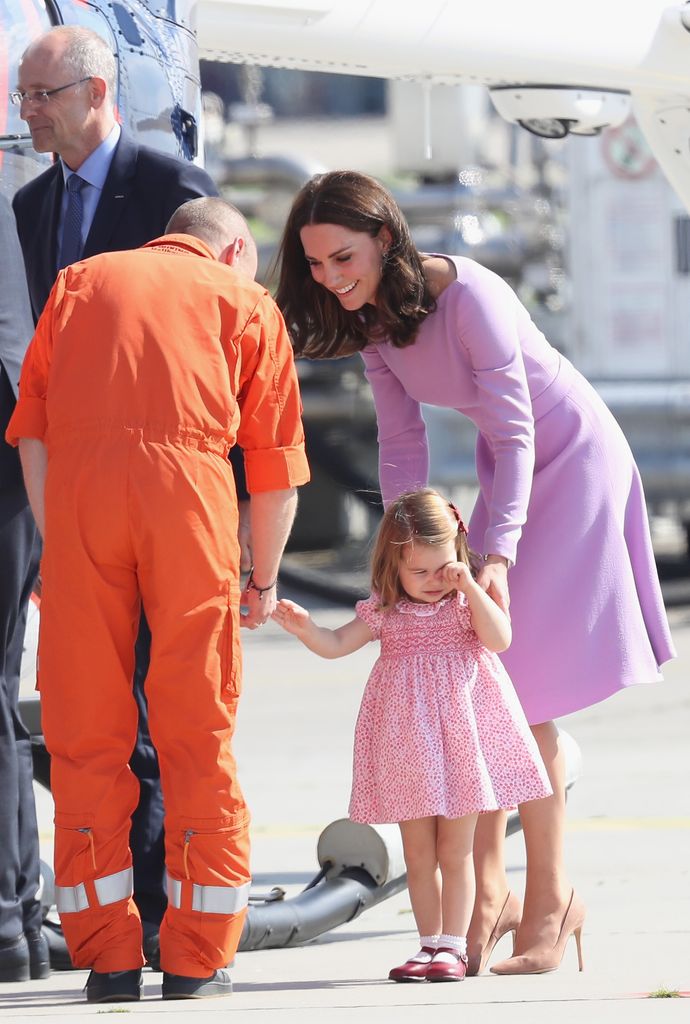 Kate talking to helicopter operator in orange suit while calming charlotte who cries
