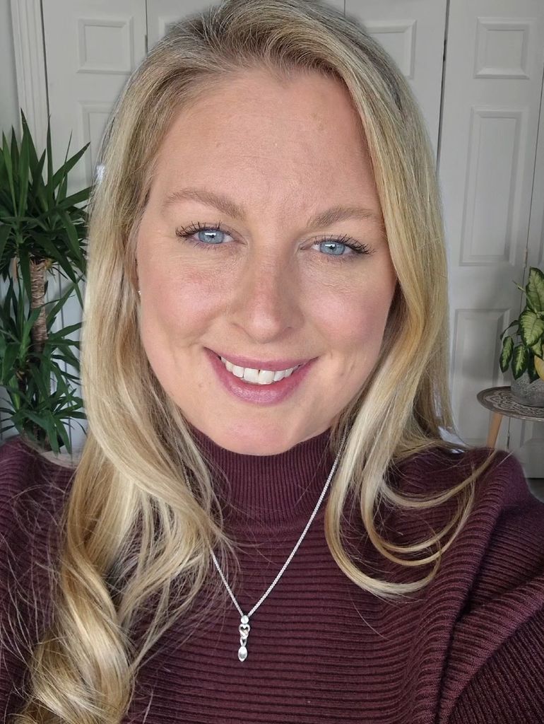 selfie of a smiling blonde woman in a polo neck
