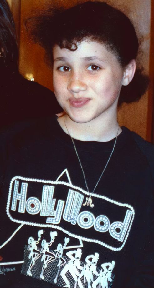 A young Meghan Markle with curls in a black Hollywood t-shirt