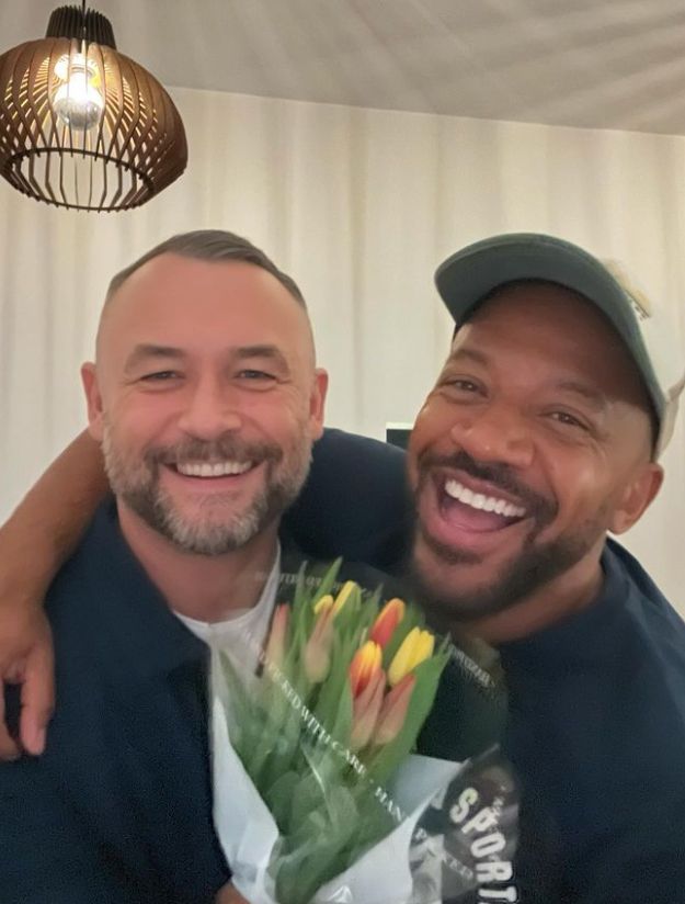 Craig Rowe with his arm around Paul White, who holds a bouquet of flowers