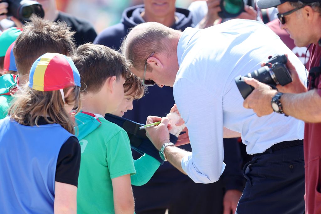 Prince William signs a child's plaster cast on Fistral Beach 