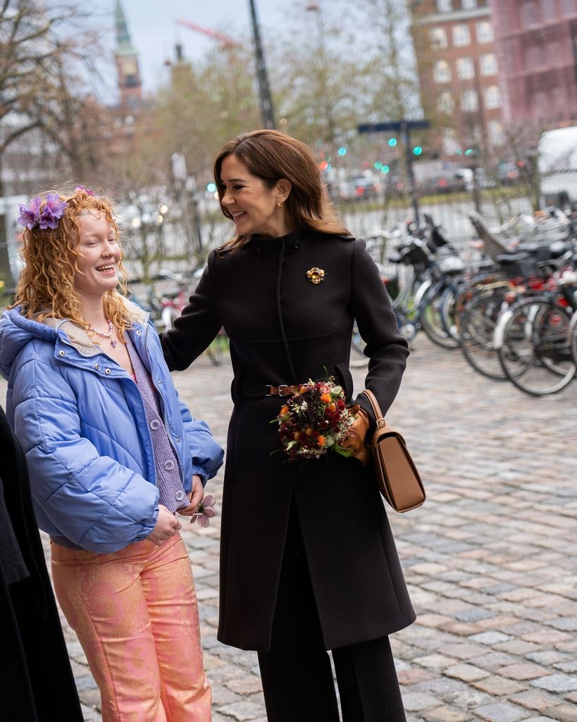 queen mary in coat smiling at young girl