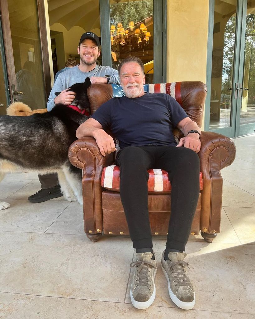 Chris Pratt and Arnold Schwarzenegger pose for a photo with the family's pet dog on the porch of the latter's home, shared on Instagram