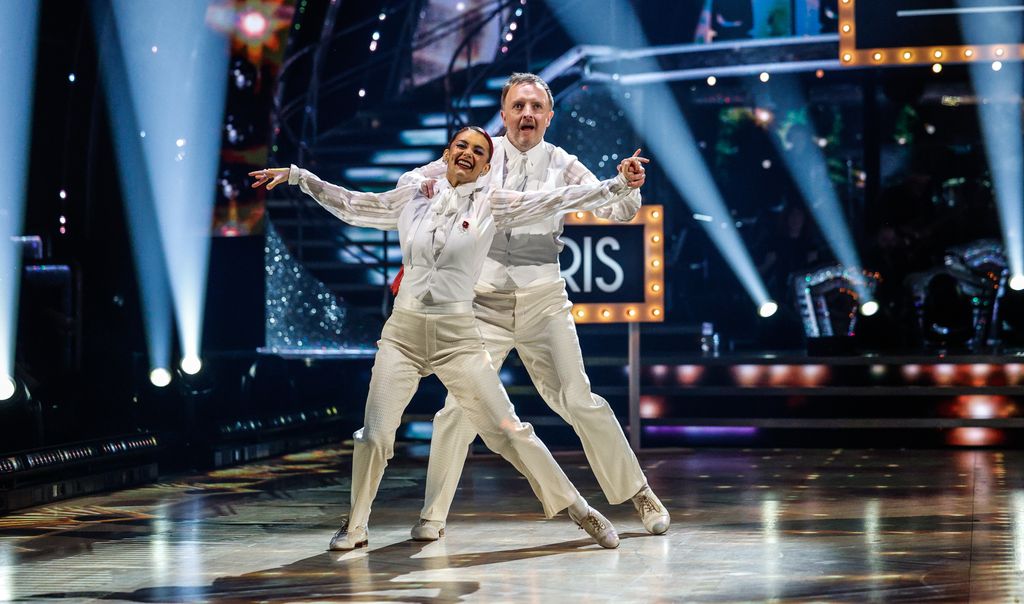 Chris McCausland and Dianne Buswell dancing in white suits