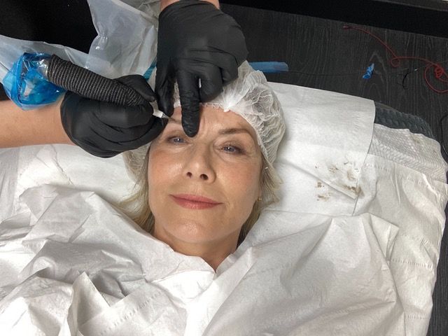 Woman having her eyebrows tattooed