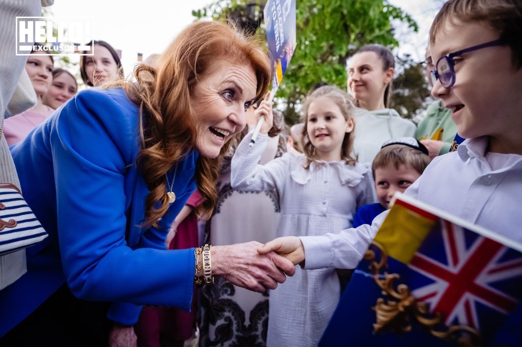 Duchess of York in blue blazer shaking Ukranian orphan refugee's hand 