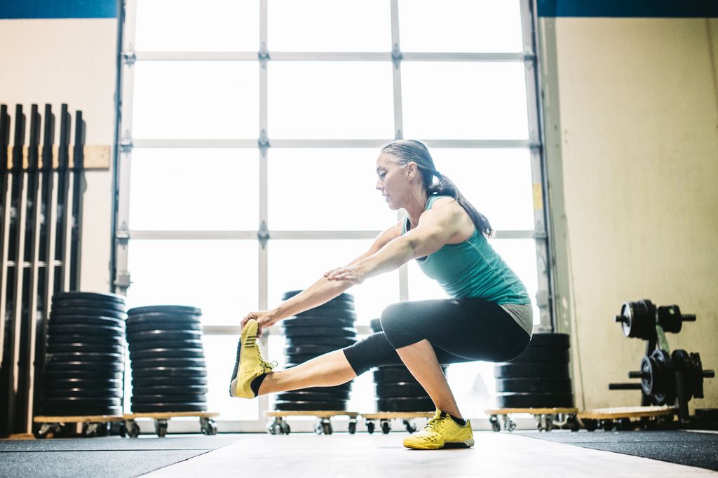 middle-aged woman doing pistol squat in gym