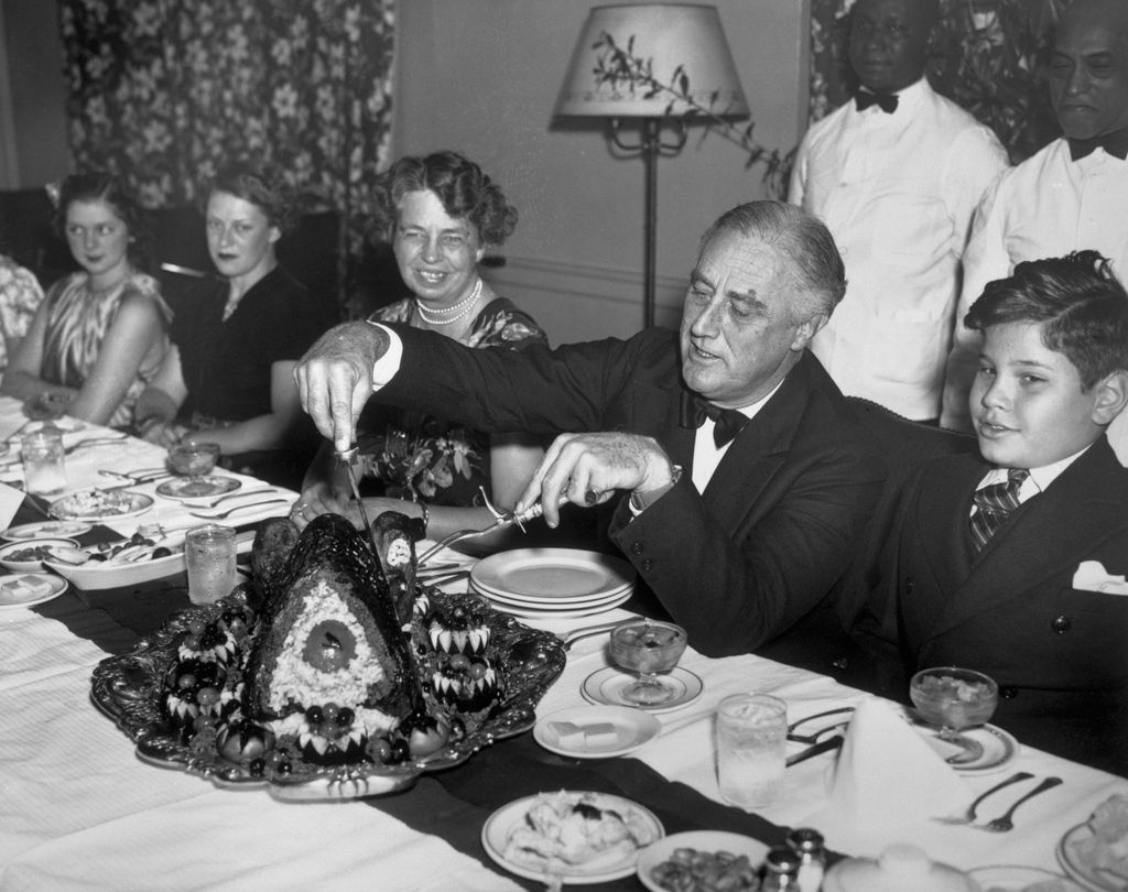 Franklin Delano Roosevelt cutting a turkey for Thankgiving dinner next to his wife Eleanor Roosevelt on November 25, 1938