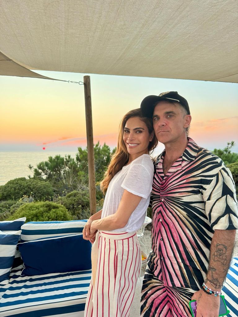 Ayda Field Williams and Robbie Williams posing in front of a sunset in Portugal