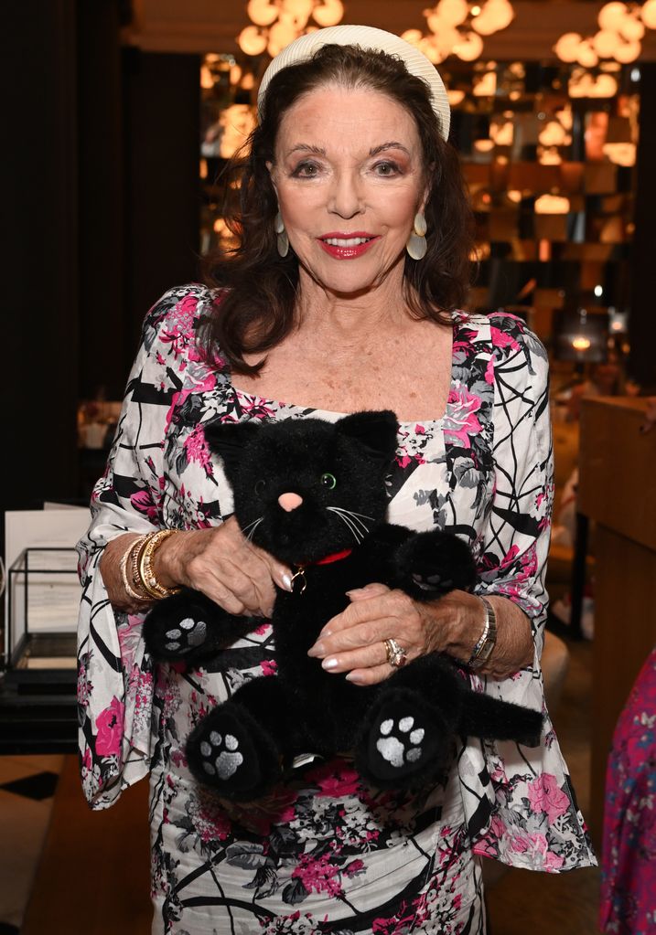 Dame Joan Collins looks lovely in colorful dress and cream headband