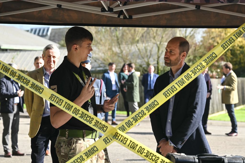 Prince William speaking with a student in front of crime scene tape