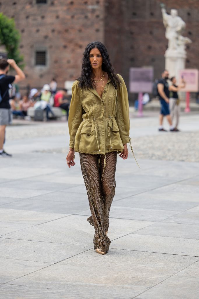 A guest wears net pants, belted green jacket outside Alberta Ferretti during the Milan Fashion Week - Womenswear Spring/Summer 2024 on September 20, 2023 in Milan, Italy. (Photo by Christian Vierig/Getty Images)
