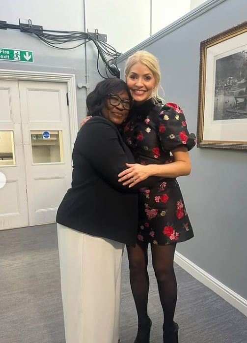 Holly Willoughby in a floral minidress hugging a woman