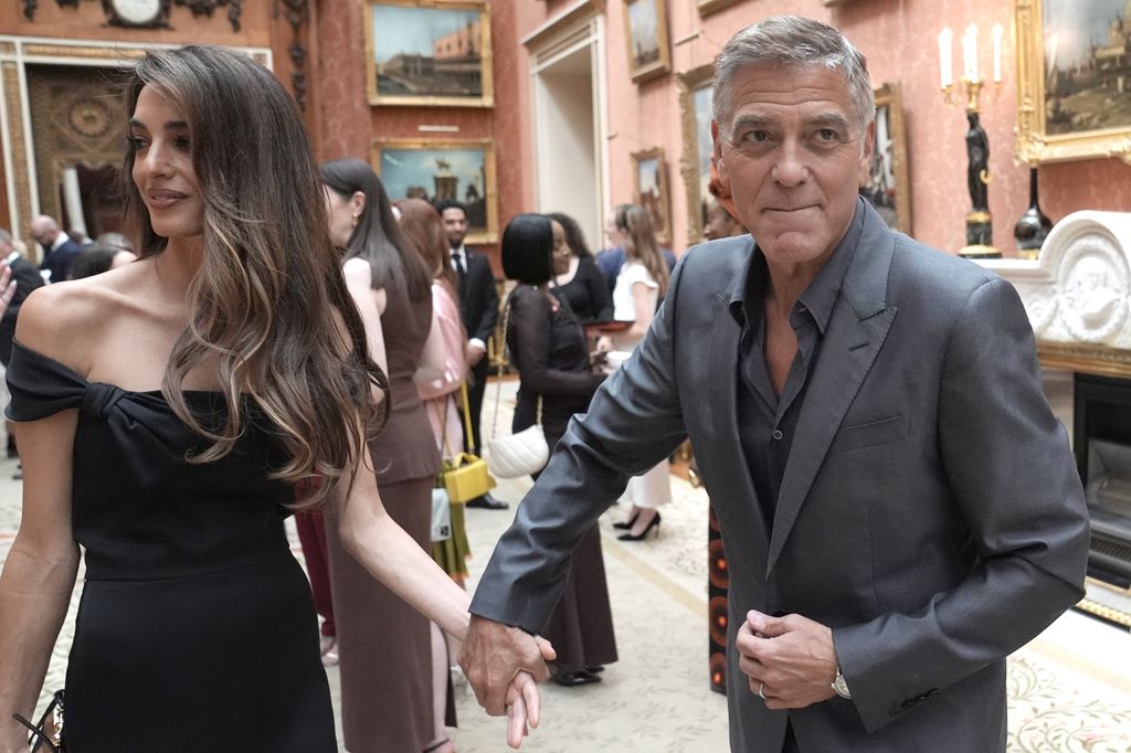 Amal Clooney wearing black dress and George in grey suit
