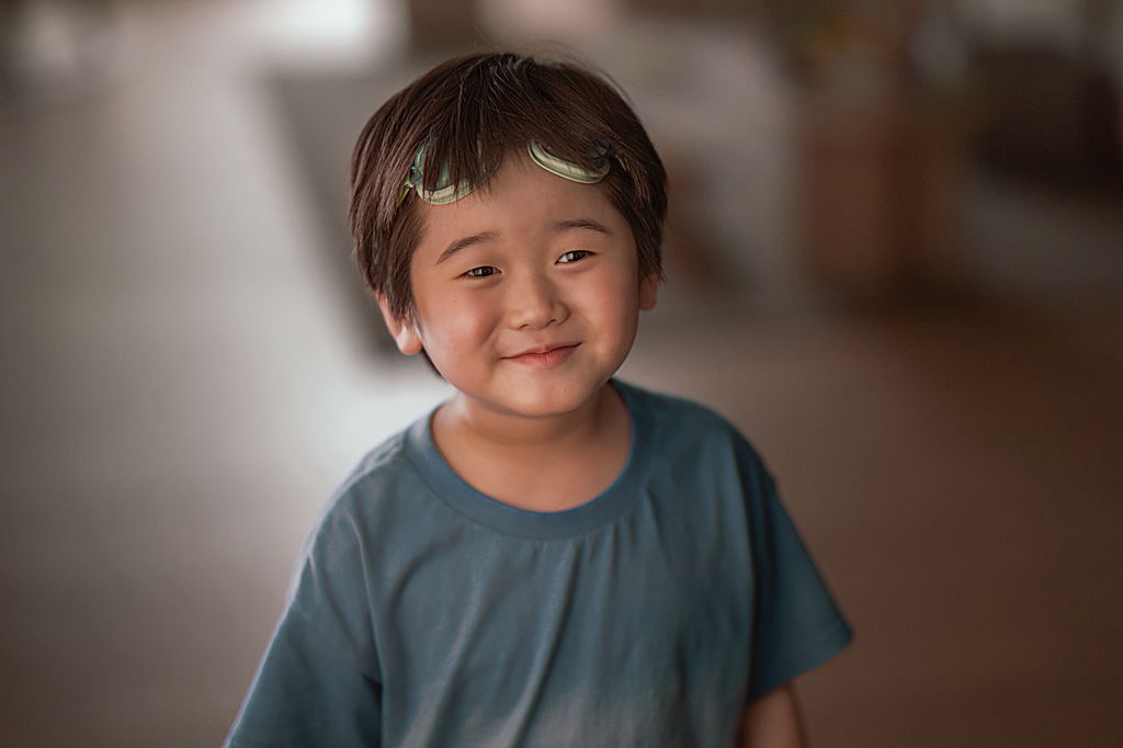 A boy smiles with goggles on his head 