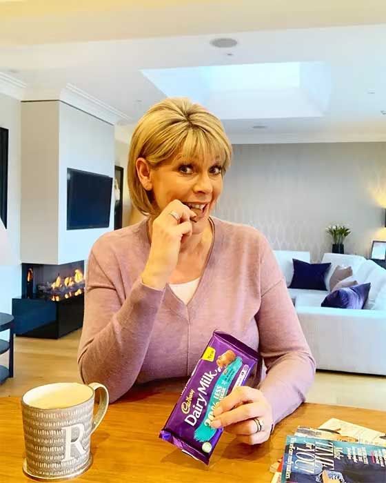1 ruth langsford sits in a living room with a fireplace