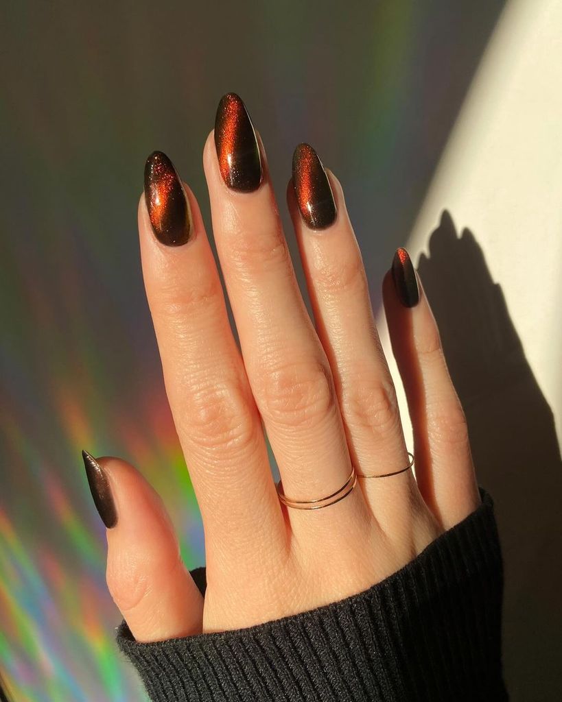 Cat Eye Glow: Almond nails with a black polish that shifts to a copper-red glow under light, giving a mesmerizing cat-eye effect, ideal for adding mystery and allure to any look.