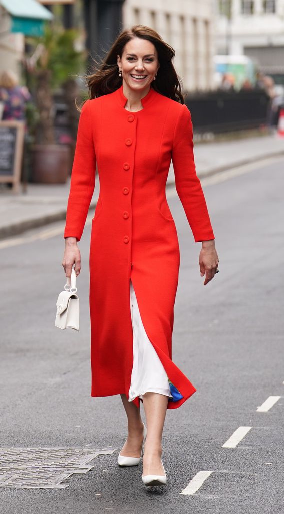 Kate Middleton smiling wearing a red coat