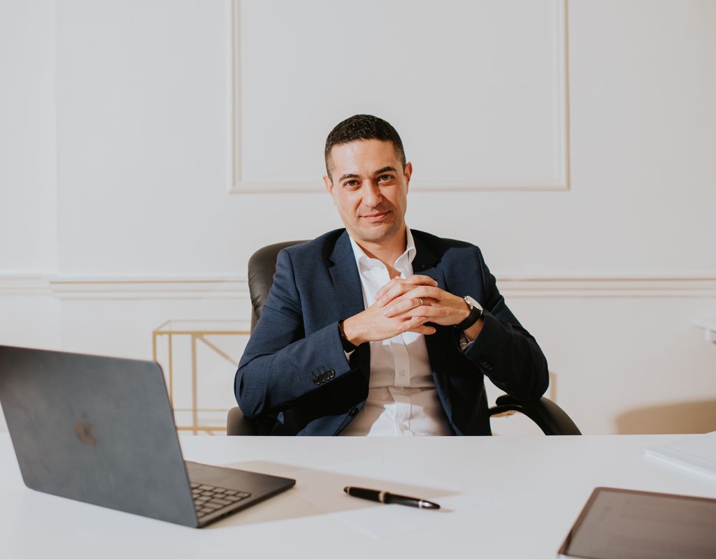 Man sitting at a desk in a white shirt and blue blazer