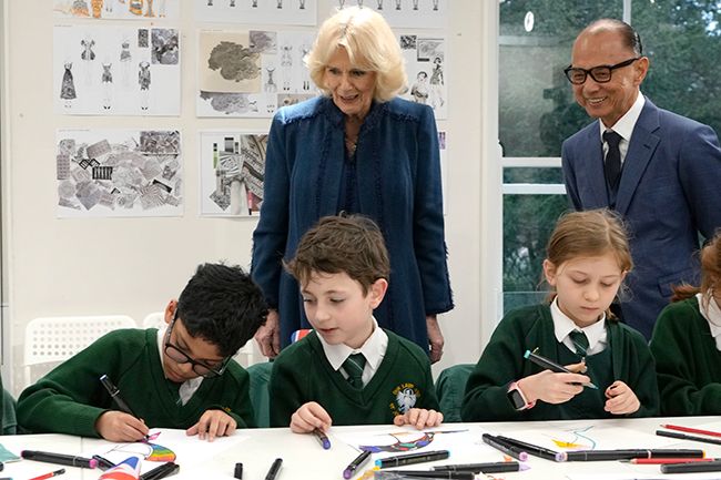 Queen Consort Camilla and Jimmy Choo behind a group of school children
