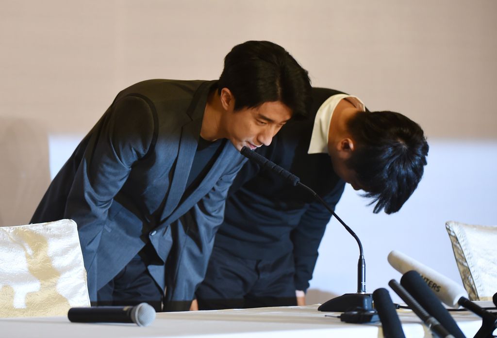 Jaycee Chan, the son of Hong Kong actor Jackie Chan, and his manager (name unavailable) bow at the beginning of a press conference in Beijing on February 14, 2015 following his release from jail. Chan was released from jail on February 13 after serving a 