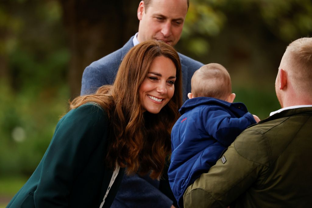 women crouching down to baby in a man's arms