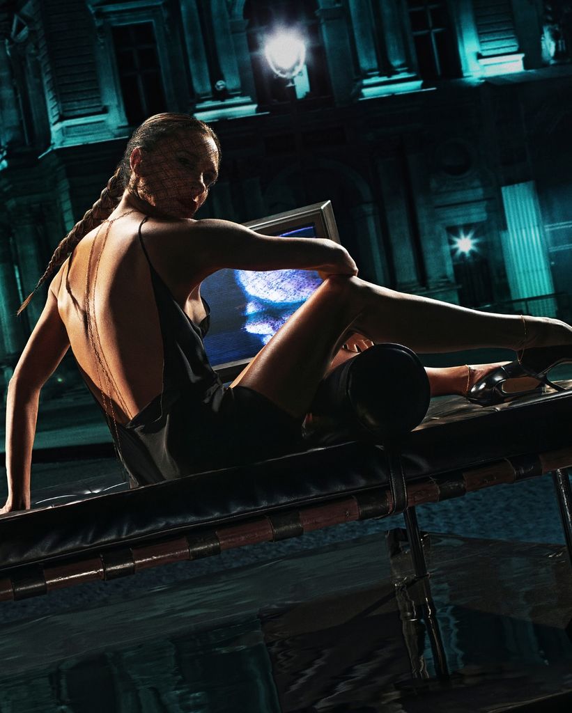 Victoria Beckham poses on a leather chaise lounge in a black mini dress 