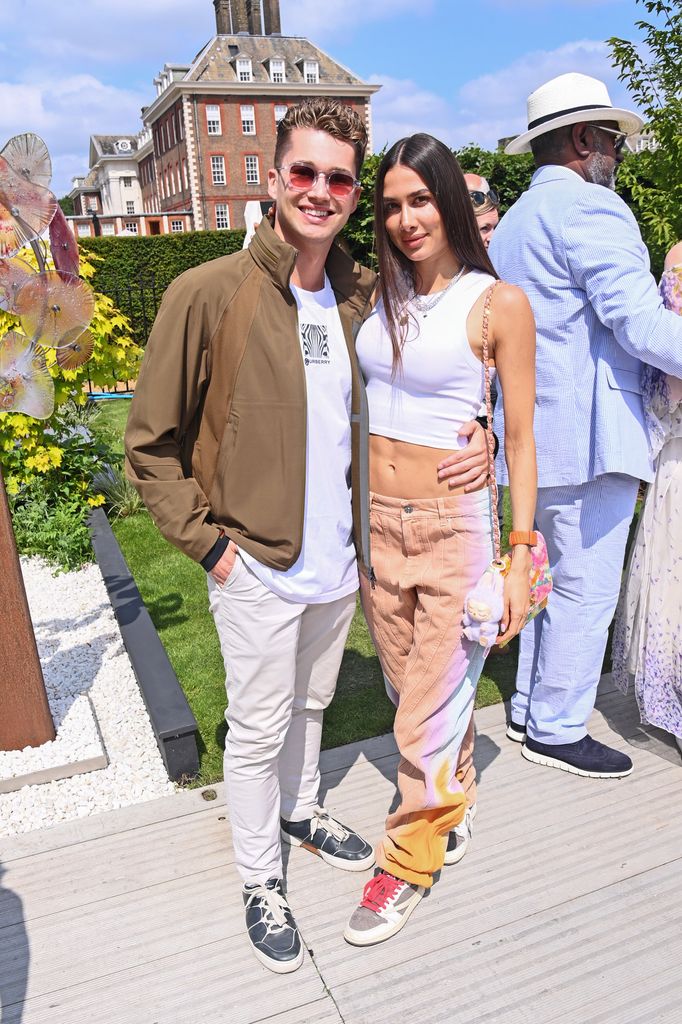 AJ Pritchard and Zara Zoffany at Chelsea Flower Show 2025 wearing relaxed streetwear looks with bomber jacket, crop top, cargo-style trousers and mismatched sneakers.