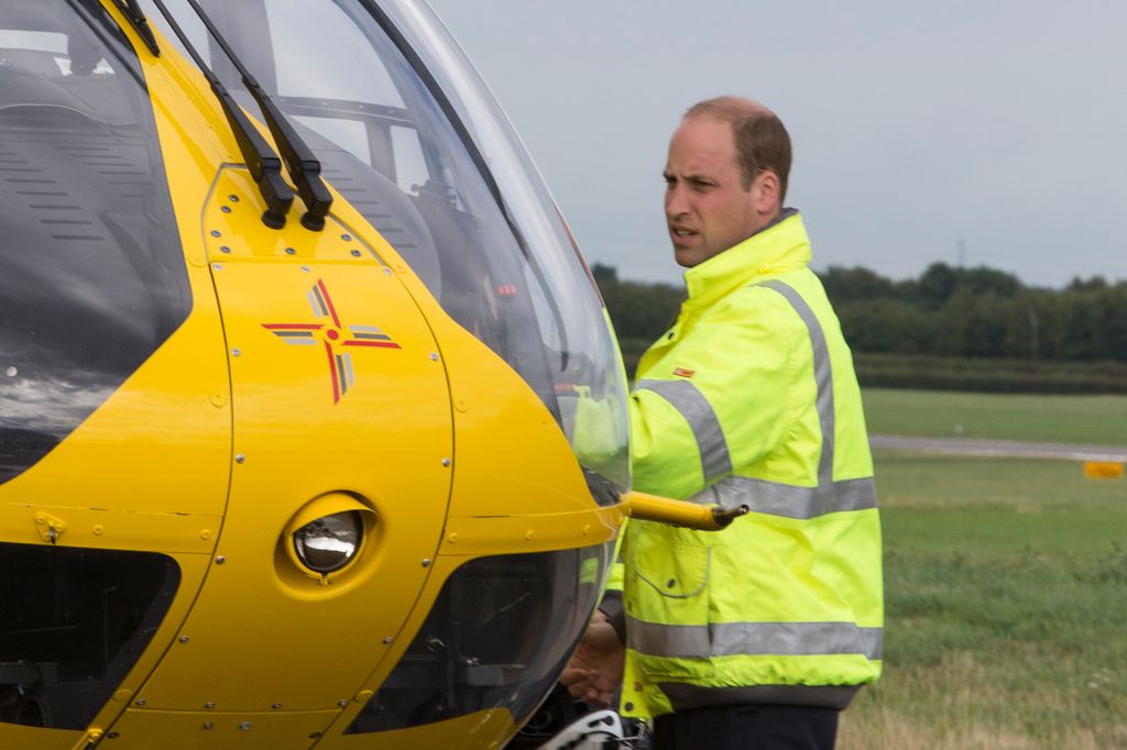 Prince William standing with a yellow helicopter
