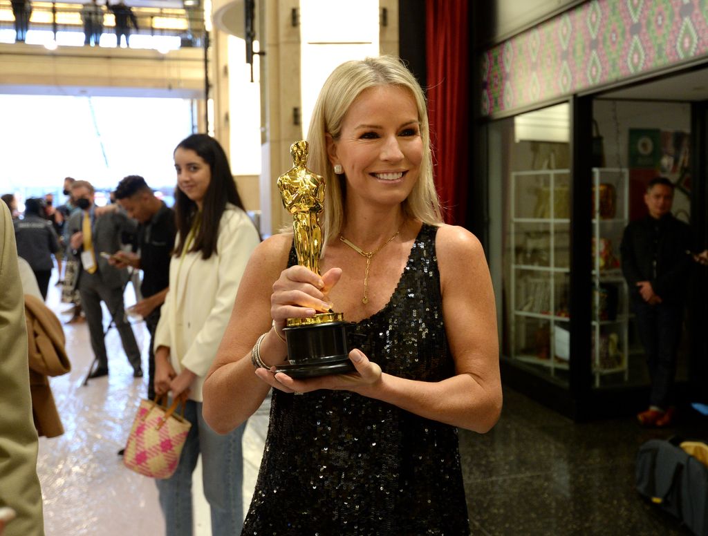Jennifer Ashton holding an Oscar in a black dress