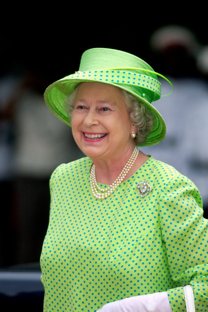 he Queen Is Wearing A Lime Green Dress With Blue Polka Dots And A Geen Hat Trimmed With Material To Match The Dress.